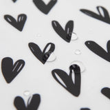 Bumkins Wet/Dry Bag: Hearts features black heart patterns on white waterproof fabric, accented by scattered water droplets.