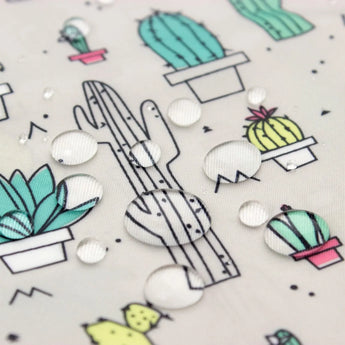 Water beads on Bumkins Sleeved Bib: Cacti, featuring cartoon cacti pots and an adjustable fit.