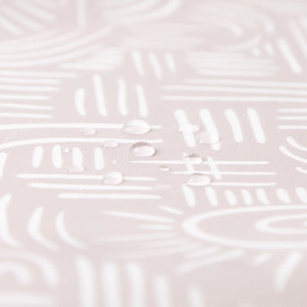 Close-up of droplets on Bumkins Splat Mat: Wander, revealing a white abstract pattern on the pale waterproof surface.