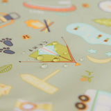 Close-up of rain droplets on the Bumkins Junior Bib: Camp Gear, with camping designs like tents and campfires on green waterproof fabric.