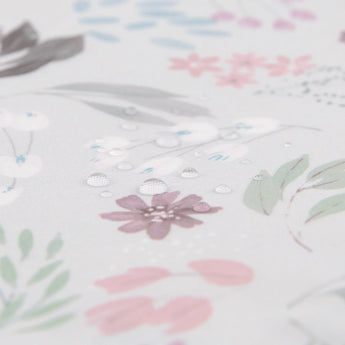 Close-up of water droplets on the SuperBib®: Floral by Bumkins, featuring a pastel floral pattern with pink, green, and brown leaves.