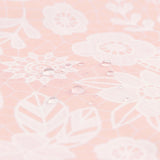 Close-up of water droplets on a peach-colored Bumkins Wet Bag: Lace, featuring a white floral pattern.