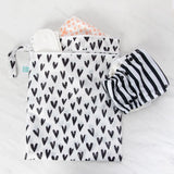 Waterproof Bumkins Wet/Dry Bag: Hearts, holds striped cloth diaper and more on a light surface.