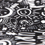 The Be Kind splat mat by Bumkins features black with white doodles like hearts and suns, made of waterproof fabric, ideal for creativity.