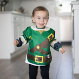 A toddler beams in the kitchen wearing a Bumkins Sleeved Bib: Zelda™, an adventure-themed, green and brown waterproof costume.