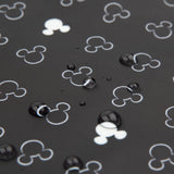 Close-up of water droplets on a black surface with Mickey Mouse shapes from Bumkins Sleeved Bib: Mickey Mouse Icon Black + White.