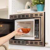 A hand places a Clay Silicone Feeding Set by Bumkins into a built-in stainless steel microwave oven.