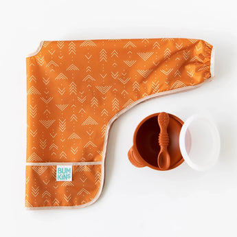 Orange-patterned bib, Bumkins Silicone First Feeding Set: Clay with matching spoon and clear lid on white background.