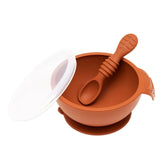 Bumkins Silicone First Feeding Set: Clay, with baby spoon inside the bowl and a transparent lid beside it.