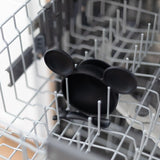 A Silicone First Feeding Set shaped like Mickey Mouse Classic Black from Bumkins sits nestled in a dishwasher rack.