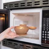 Placing a Bumkins Minnie Mouse Gold Silicone First Feeding Set bowl into a microwave.