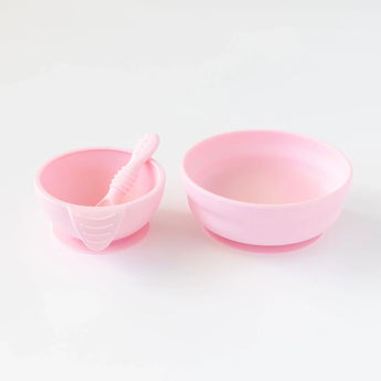 Two pink Silicone First Feeding Sets by Bumkins, one with a spoon and suction base for easy feeding, shown on a white background.