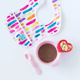 Colorful baby bib, Bumkins Silicone First Feeding Set: Pink with suction base, a bowl of brown puree, star cereal, and heart cup.