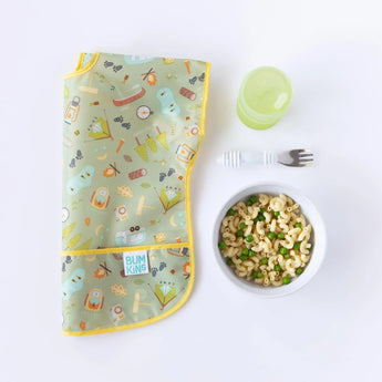 A vibrant bib, Bumkins Marble Silicone Grip Bowl of mac & peas, green cup, and toddler fork on a white surface.