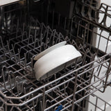 Open dishwasher rack with two white plates and a Bumkins Marble Silicone Grip Bowl, ideal for self-feeding toddlers.