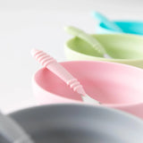 Close-up of Bumkins Silicone Grip Bowls with matching spoons; pastel pink, green, and blue, featuring suction bases.