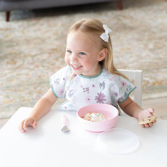 A happy toddler enjoys ice cream in a Bumkins Silicone Grip Bowl: Pink, paired with a cookie.