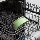 Open dishwasher with a green plate and Bumkins Silicone Grip Bowl: Sage on the bottom rack, ensuring items stay in place.