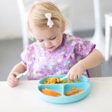 Toddler enjoys macaroni and veggies on Bumkins Silicone Grip Dish: Blue with a fork; suction base ensures it stays put.