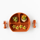 Bumkins Silicone Grip Dish: Clay with star snacks, kiwi slices, veggie sticks in hummus, and matching utensils on a white background.