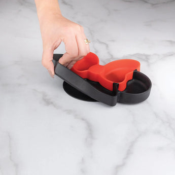 A hand holds a Bumkins Minnie Mouse Silicone Grip Dish, butterfly-shaped, on a marble surface.