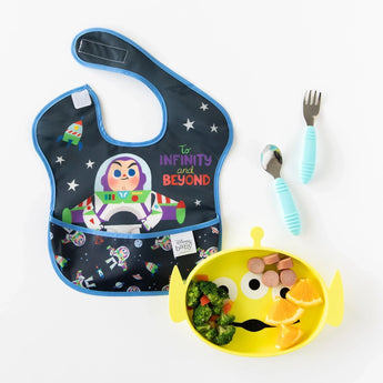 Blue Buzz Lightyear bib, Toy Story Alien Bumkins silicone plate with fruits, veggies, sausages. Toddler utensils are by the plate.