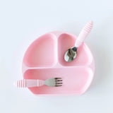 The Bumkins Silicone Grip Dish in pink, featuring 3 sections with a spoon and fork, is perfect for toddlers to self-feed.