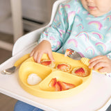 Child in highchair, wearing a rainbow shirt, enjoying waffles and strawberries from a Bumkins Pineapple Silicone Grip Dish for toddlers.