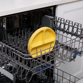 Inside the open dishwasher with gray racks, Bumkins Pineapple Silicone Grip Dish ensures toddler portions stay in place.