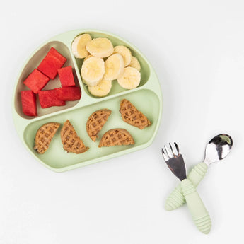 A Sage Silicone Grip Dish by Bumkins holds watermelon, banana slices, and waffles for toddlers on a white background.