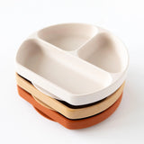 A stack of four round Silicone Grip Dish plates in white, beige, and terracotta is set against a white background.