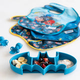 Bumkins Batman Blue Silicone Grip Dish with banana, berries, yogurt. Stacked superhero bibs and blue utensils in the background.