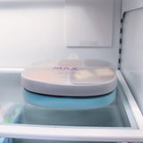 A blue silicone dish by Bumkins with a leak-resistant lid labeled MAX on a fridge shelf.