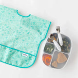 Kids meal in a Bumkins Silicone Grip Dish (Marble) with 5 sections, including broccoli and sandwich, plus a green bib and utensils.