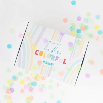 Colorful confetti surrounds a white Bumkins Ultimate Gift Set - Floral & Lace box with rainbow design, Chewtensils, and Making Life Colorful.