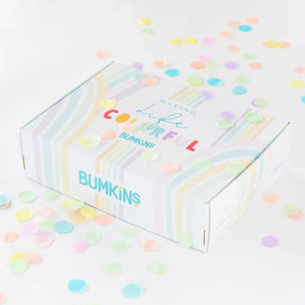 A vibrant Bumkins Ultimate Gift Set - Floral & Lace box on a white surface, surrounded by colorful confetti, features charming SuperBibs.