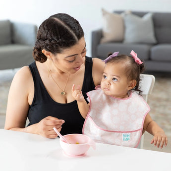 Mom and toddler with matching pink Ultimate Gift Set - Floral & Lace sit at a table. Mom smiles as toddler shows fingers near their Grip Dish.