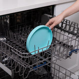 Someone places a Blue Silicone Grip Plate by Bumkins securely in an open dishwasher.