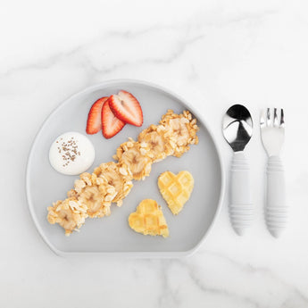 Kids meal on a Bumkins Silicone Grip Plate: banana, rice cakes, chia yogurt, strawberries, and heart-shaped waffles.