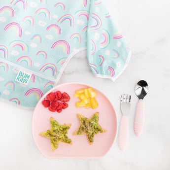 Bumkins Silicone Grip Plate: Pink with star snacks, a rainbow baby bib, and raspberries on marble—a perfect mealtime set.