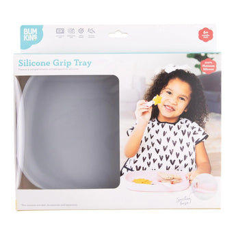 Child smiles with Bumkins Silicone Grip Tray, holding a star snack. The food-safe gray tray has a strong suction base.