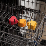 The Bumkins Silicone Little Dipper 3-Pack: Tutti-Frutti features star-shaped, food-grade caps in red, orange, and yellow on the top rack.