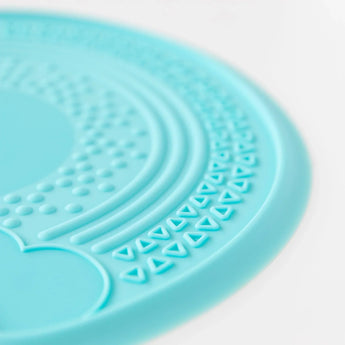 Close-up of the Bumkins Blue Silicone Sensory Placemat with dot and triangle texture on round surface.