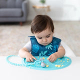 A toddler playfully explores bites on the Bumkins Silicone Sensory Placemat: Blue.