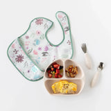 SuperBib®: Floral by Bumkins, fork/spoon set, and sectioned plate with strawberries, apple dice, cheesy omelet.