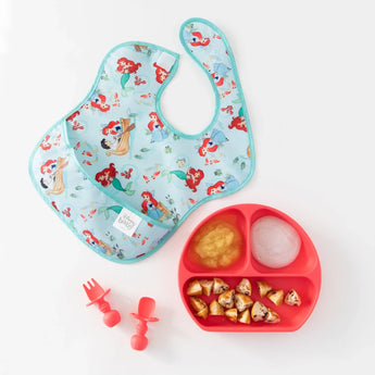 A colorful SuperBib® 3-Pack featuring Ariel, with waterproof fabric, paired with a red plate and pink utensils on a white background.