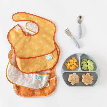 SuperBib® 3 Pack: Desert Boho, a gray divided plate with snacks, and a baby cutlery set on a white background.