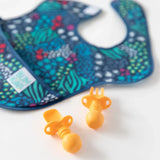 Bumkins SuperBib® 3 Pack: All Together Now with colorful dots and two orange rubber baby utensils on a white background.