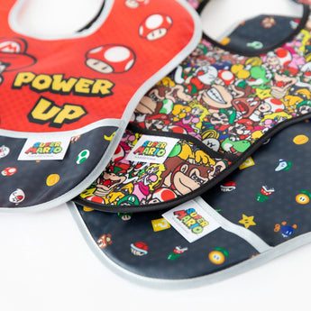 Bumkins SuperBib® 3 Pack: Super Mario™ Power-Up with Mario and mushrooms, made of easy-wipe fabric, on a white surface.