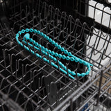 A Bumkins silicone accessory tether in blue sits on the top rack of an open dishwasher.